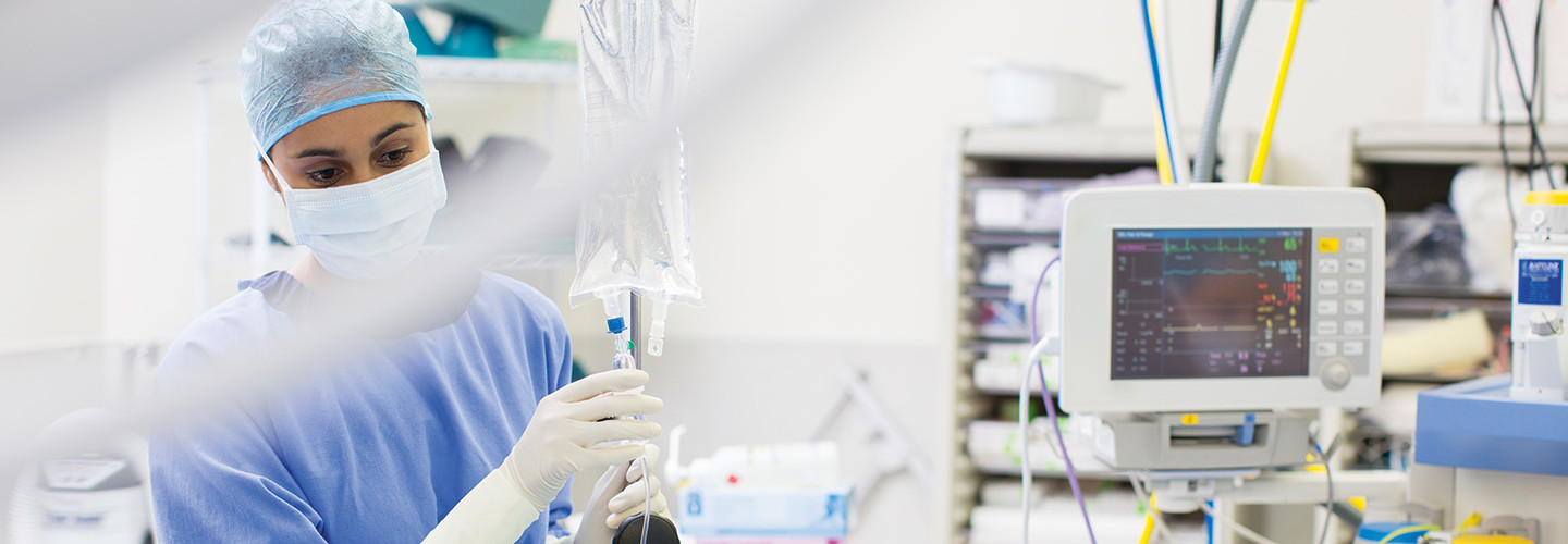 Nurse moves IV drip into patient room with other medical devices