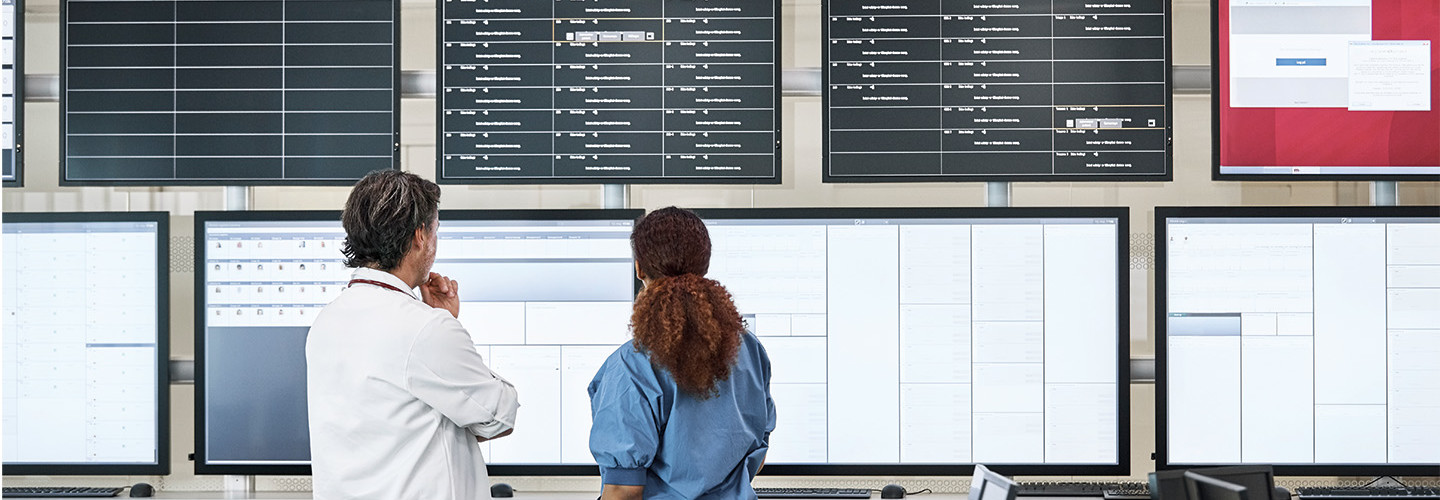 Nurse and doctor consider information on multiple screens